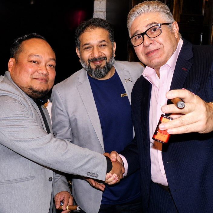 Members sharing cigars and a handshake at a DMV Cigar Club evening